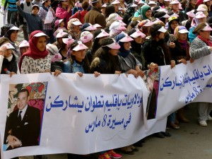 Manifestantes arborant une banderole flanquée de portraits de l'actuel roi du Maroc Mohammed VI